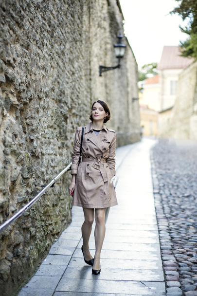 Femme au manteau beige près du vieux mur de la ville
 - Photo, image