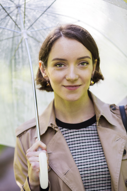 Γυναίκα στο παλτό κάτω από ομπρέλα δεδομένου ότι βρέχει - Φωτογραφία, εικόνα