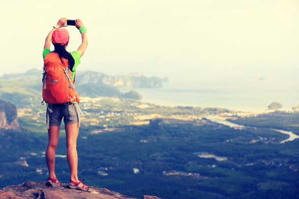 young woman hiker taking photo - 写真・画像