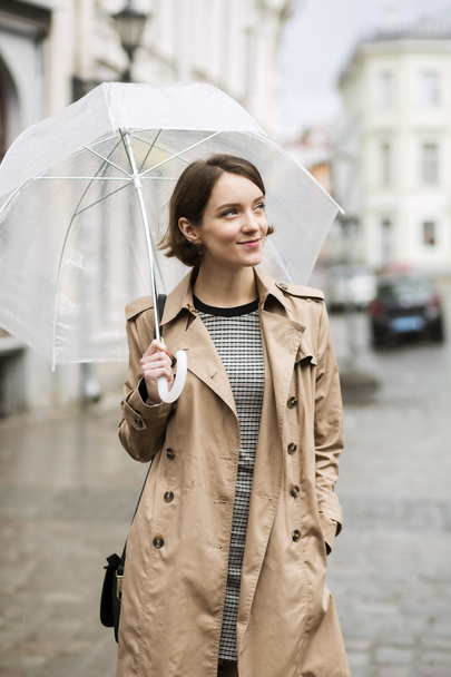 Woman at coat on wet street after rain - Foto, Imagen