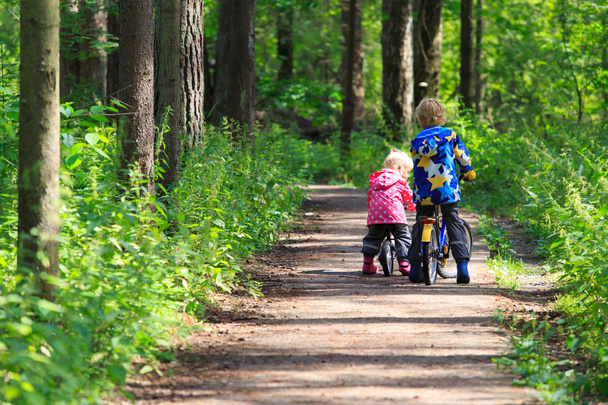 kids sport - little boy and girl riding bikes in forest - Foto, Bild
