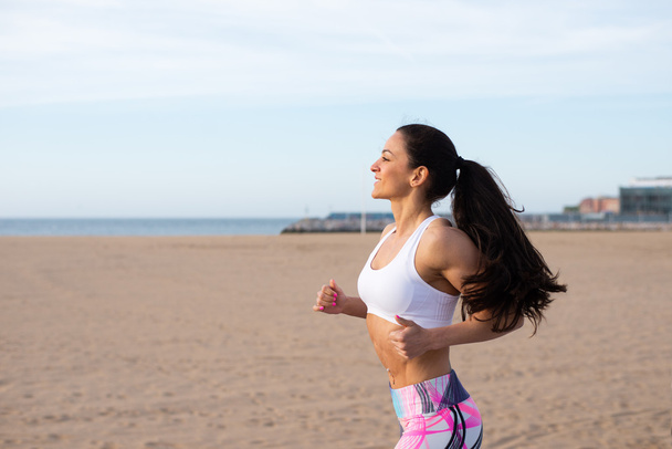 Cheerful fitness woman running at the beach - Fotó, kép