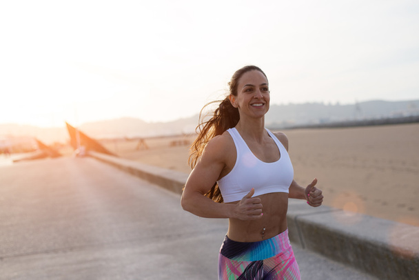 Fröhliche Fitness-Frau läuft bei Sonnenuntergang - Foto, Bild