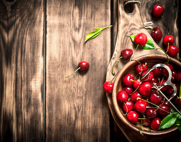 Red cherry in the Cup and metal tool for cherries. - Foto, afbeelding