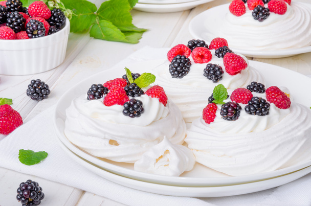Habcsók sütemények Pavlova a felvert tejszín és a friss bogyós gyümölcsök - Fotó, kép