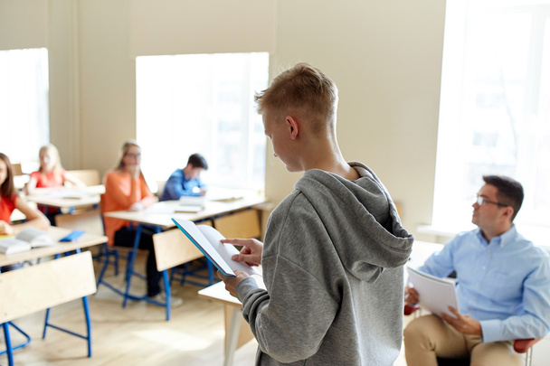 μαθητής αγόρι με το σημειωματάριο και δάσκαλος στο σχολείο - Φωτογραφία, εικόνα