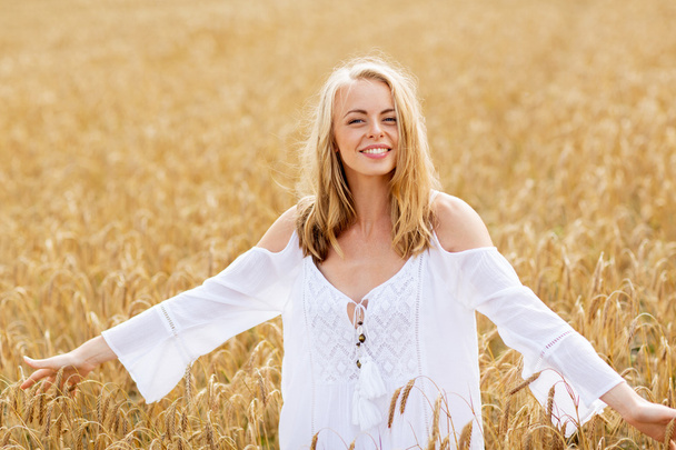 glimlachende jonge vrouw in witte jurk op graanveld - Foto, afbeelding