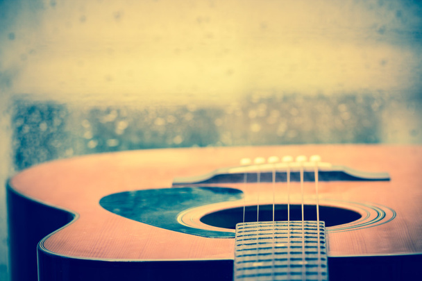 Акустична гітара біля вікна з краплями води
 - Фото, зображення