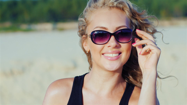Retrato de una joven atractiva sonriendo, mirando a la cámara, posando en la playa
 - Metraje, vídeo