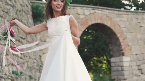 Happy bride in wreath walking and posing with bouquet near castle. Slowly - Filmagem, Vídeo