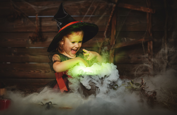 Halloween. lapsi tyttö noita valmistelee taikajuomaa pata
 - Valokuva, kuva