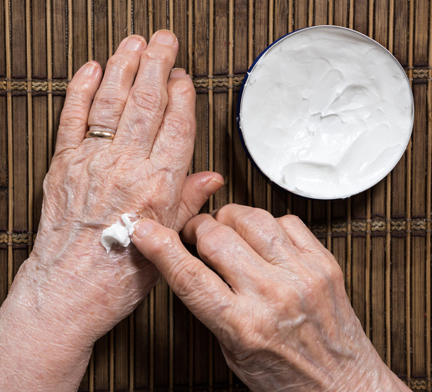 Old womans  hands applying cream  - Foto, immagini