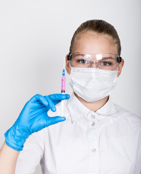 close-up little girl in a medical dress and gloves holding a syringe - 写真・画像