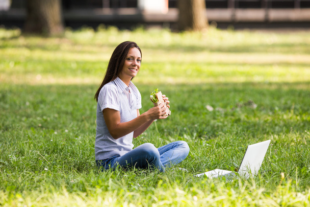 businesswoman eating sandwich in park - Foto, imagen
