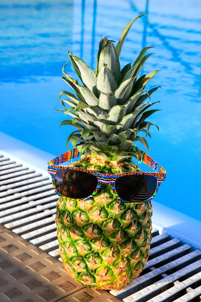Pineapple wearing sunglasses at swimming pool - Photo, Image