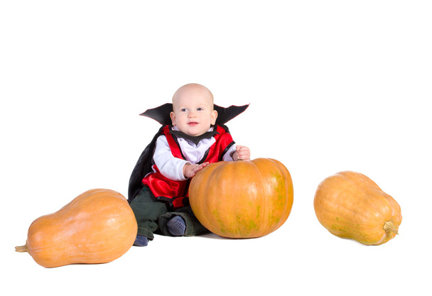 Baby boy in black halloween cloak playing with pumpkin - Foto, Imagen