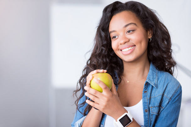 Positive young woman holding an apple. - Zdjęcie, obraz