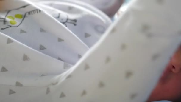 Newborn in white baby clothes lying in a bad and moving his hands - Footage, Video