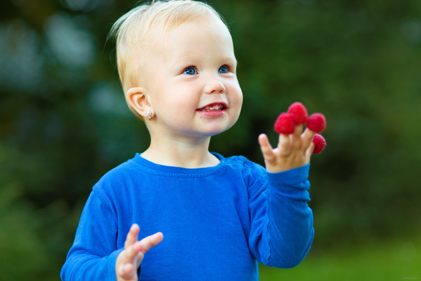 Young girl is holding raspberries on her fingers - Foto, immagini