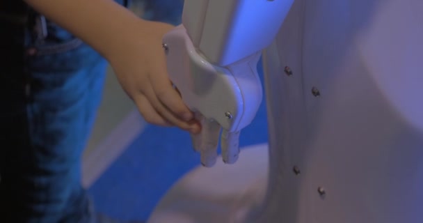 Close-up van jongen hand houdt witte kunststof hand van humanoïde robot robotica tentoonstelling in Moskou, Rusland - Video