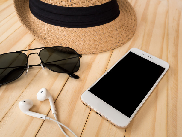 Concepto de accesorios de viaje. Smartphone, auriculares, gafas de sol, sombrero
 - Foto, Imagen