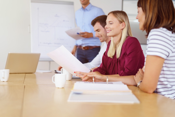 Smiling woman with coworkers at desk - Photo, Image