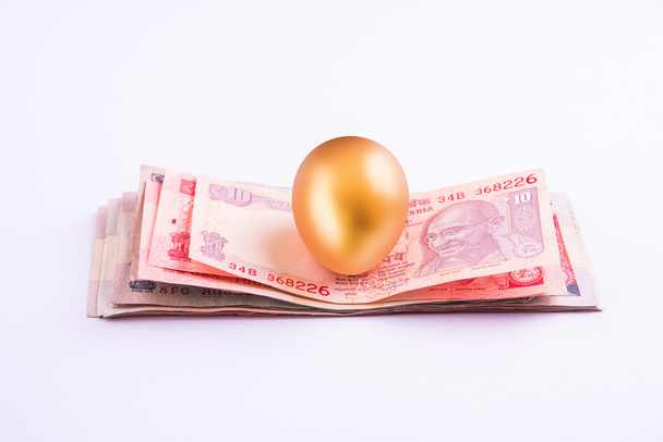 A gold egg on a pile of indian currency notes - Photo, Image