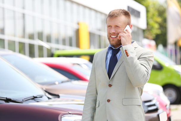 Man talking on phone on new cars background - Foto, Imagen