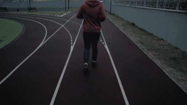 Young man running on the track following shot - 映像、動画