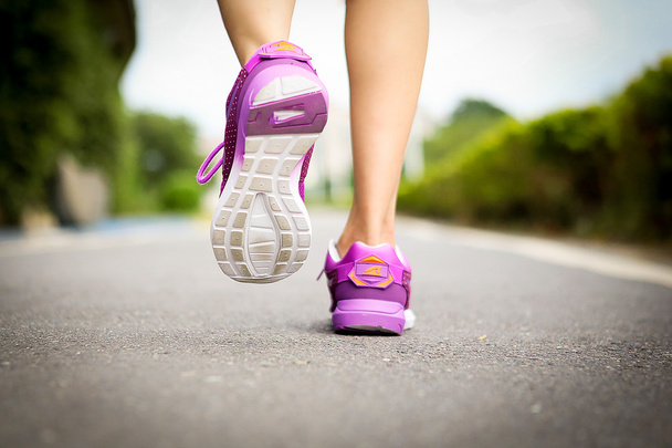 Der Sportler läuft mit den Füßen auf der Straße in Nahaufnahme auf Schuhen. Frau Fitness Jog Workout Wellness Konzept. - Foto, Bild