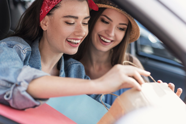 mujeres sentadas en un coche con sus compras
 - Foto, Imagen