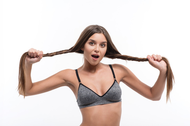 Cheerful girl checking strength of hair - Foto, afbeelding