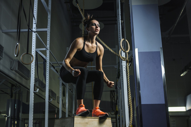 Powerful muscular woman CrossFit trainer jumps during workout at gym - Foto, Imagen