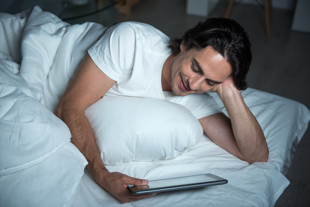 Positive man using tablet in bed - Photo, image