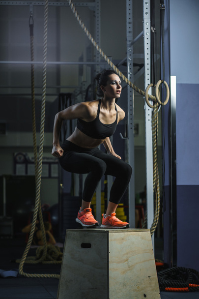 Powerful muscular woman CrossFit trainer jumps during workout at gym - Foto, immagini
