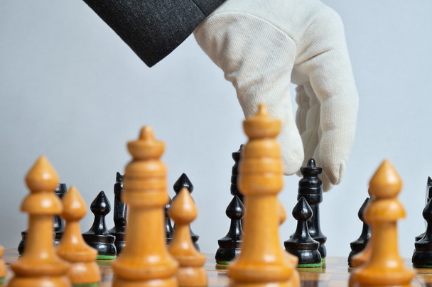 Белая перчатка перемещает шахматную фигуру
 - Фото, изображение
