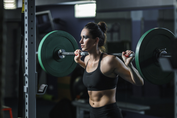 Ισχυρή ελκυστική μυώδης γυναίκα προπονητής διασταύρωση κάνει προπόνηση με μπάρα - Φωτογραφία, εικόνα