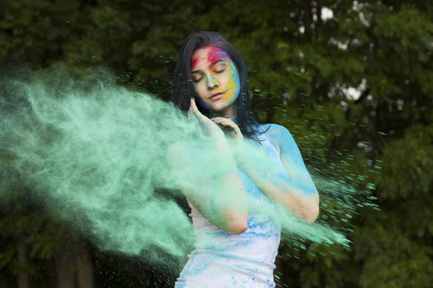 Mooi model poseren met kleur verf ontploft in de buurt van haar - Foto, afbeelding