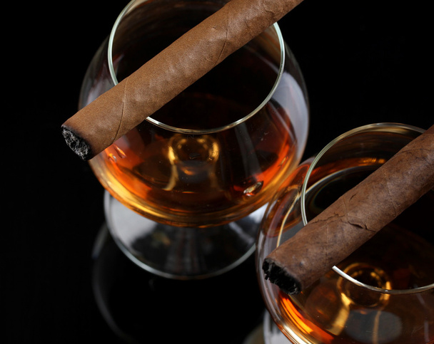 Two glasses of brandy and cigars on black background - Fotoğraf, Görsel