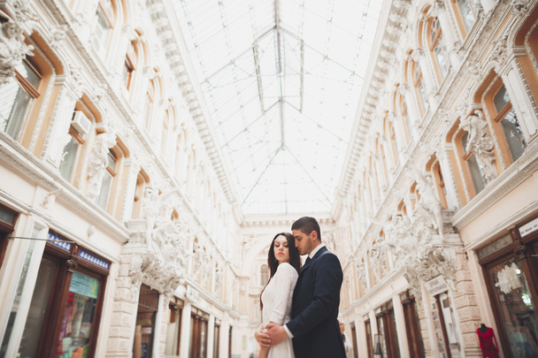 Beautiful wedding couple, bride, groom kissing and hugging against the background of old building - Foto, Bild