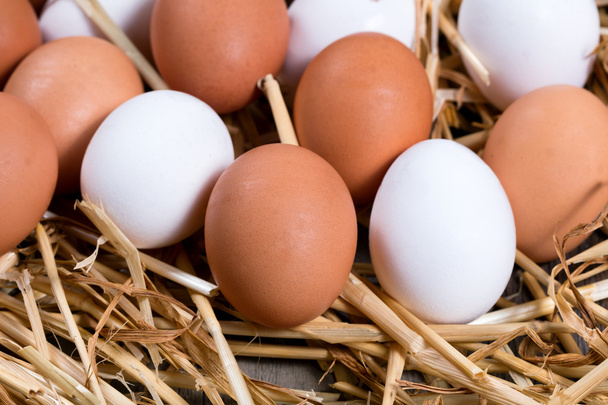 Bütün taze beyaz ve kahverengi yumurta saman üzerinde - Fotoğraf, Görsel