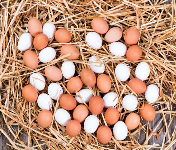 Φρέσκα αυγά ολόκληρα λευκό και καφέ στο άχυρο - Φωτογραφία, εικόνα