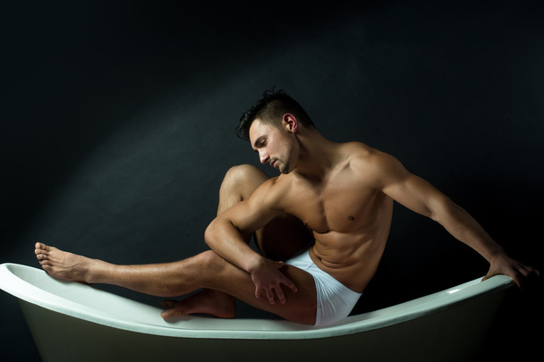 Muscular man on bathtub - Φωτογραφία, εικόνα