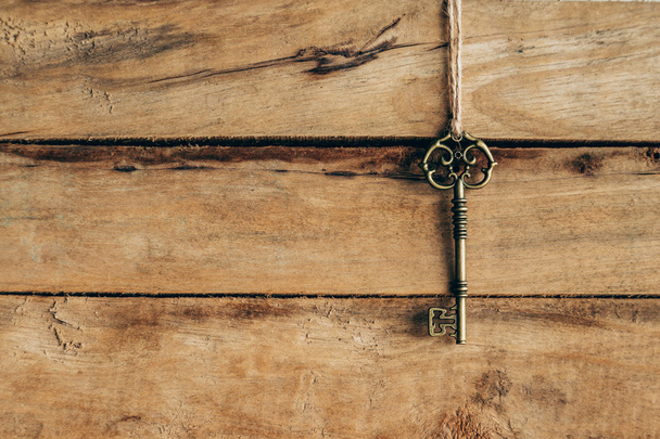 Старый ключ висит на коричневом дереве с пространством
. - Фото, изображение
