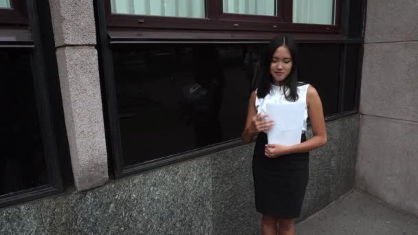 Giovane bella donna d'affari femmina ragazza ritratto guardare documenti bancarelle su sfondo ufficio edificio all'aperto
 - Filmati, video