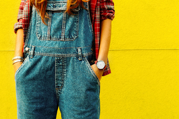 Stylish urban girl in a checkered shirt and denim overalls stand - Foto, Imagem