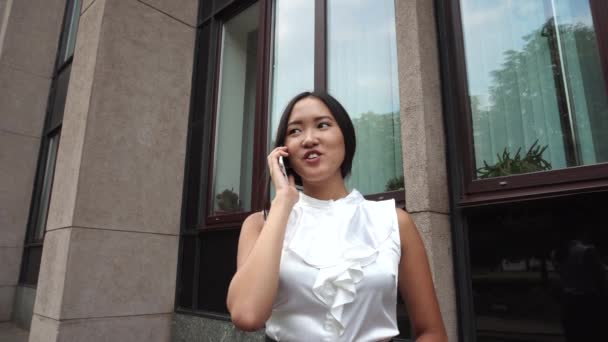 Jonge mooie zakelijke vrouw vrouwelijke meisje portret Talk op telefoon bezit zijn van documenten op de achtergrond kantoorgebouw buiten - Video