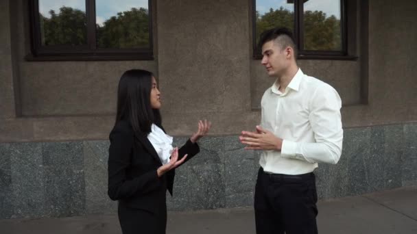 Jonge mooie zakelijke vrouw vrouwelijke meisje en Kaukasische mannelijke portret Talk onderhandelen Stands op achtergrond kantoorgebouw buiten - Video