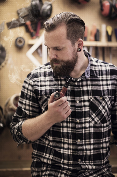 Portrait d'un homme fumeur de pipe en atelier de bois
 - Photo, image