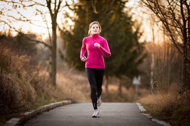 Young woman running outdoors on a lovely sunny winter/fall day - Foto, Imagen